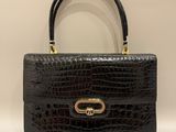 un sac à main en cuir de crocodile noir avec des finitions dorées
