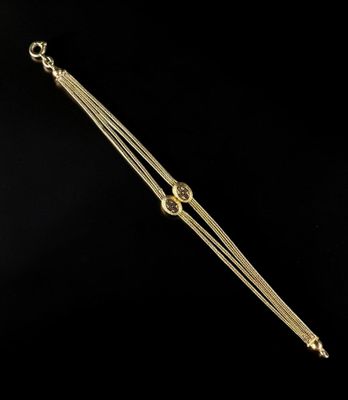 a close up of a gold plated bracelet on a black background
