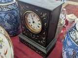 a clock sitting on a table in a room full of vases