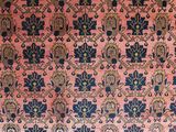 a close up of a pink and blue rug on a wooden floor