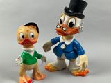 two figurines of donald duck and daisy duck are posed next to each other