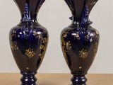 pair of blue vases with gold flowers on them sitting on a table