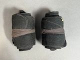 two pieces of black cloth wrapped in brown string on a white surface