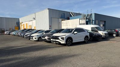 de nombreuses voitures garées sur un parking situé devant un immeuble