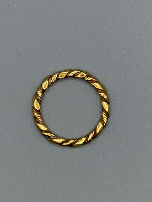 gros plan d'une bague en or sur une surface grise