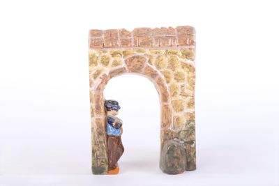 a figurine of a man standing in front of a stone arch