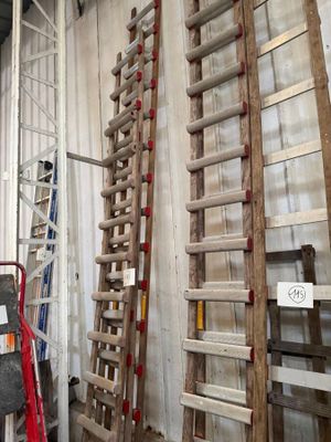 several wooden ladders leaning against a wall in a warehouse