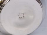 a close up of a silver vase on a white surface