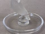 a glass bird sitting on a glass plate on a table