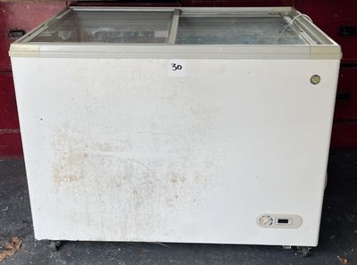 un petit réfrigérateur blanc avec une porte vitrée, devant un mur de briques