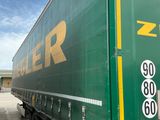 un semi-remorque vert garé sur un parking