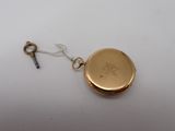 a gold pocket watch with a key attached to it