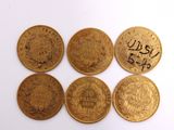 six gold coins with arabic writing on them on a white surface