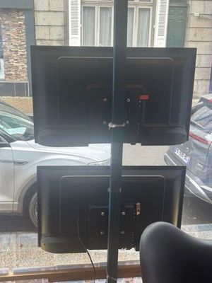 two televisions that are sitting on a stand in front of a window