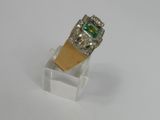 an image of a ring with a green stone on a clear stand