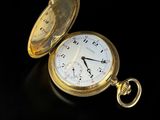 une montre de poche en or posée sur une surface noire