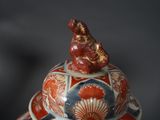 a red, white, and blue vase with a bird on top
