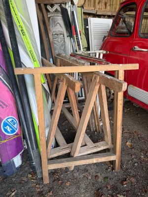une voiture rouge garée à côté d'une pile de planches de surf
