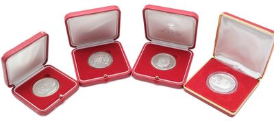 four silver coins in a red box on a white surface