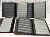 several binders are lined up on a bed with a white sheet