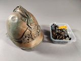 a metal helmet and a container of screws on a table