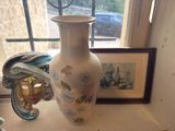 a white vase sitting on a window sill next to a picture