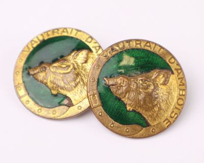 two gold and green buttons with a picture of a bear on them