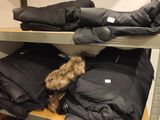 several coats and jackets are stacked on a shelf in a room