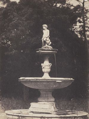 une statue au sommet d'une fontaine, au milieu d'un parc