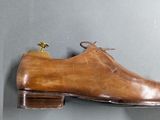 pair of brown leather shoes hanging on a wall on a gray wall