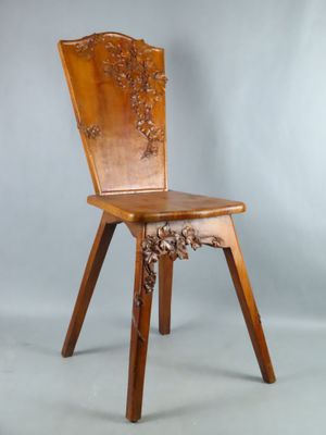 une image représentant une chaise en bois dont le dossier et l'assise sont sculptés