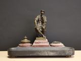 bronze statue of a man with a cane and a pot on a marble base