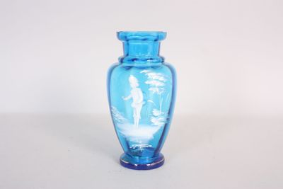 un vase en verre bleu sur lequel est représenté un homme et une femme