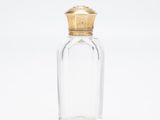 une bouteille en verre transparent avec un bouchon doré, sur fond blanc