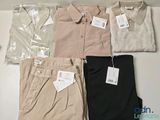 several men ' s shirts and pants are laid out on a table