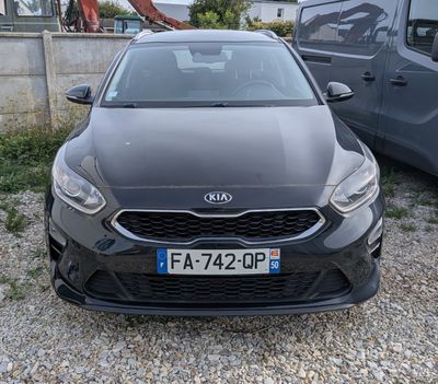 l'avant d'une voiture noire garée sur un parking en gravier à côté d'une camionnette