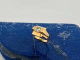 un gros plan d'une bague en or sertie d'un diamant posé sur une pierre bleue