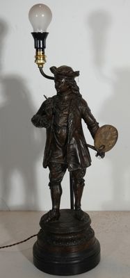 une statue en bronze représentant un homme tenant un éventail et une lampe