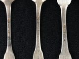 three silver spoons and a fork on a black surface