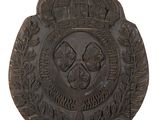 une image représentant une plaque métallique surmontée d'une couronne