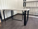 a white desk with black legs in the corner of a room