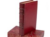 two red books sitting on top of each other on a white surface
