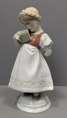 une figurine représentant une femme en train de lire un livre