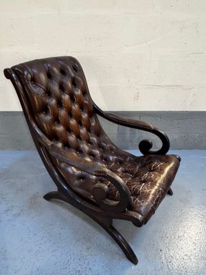 un vieux fauteuil en cuir posé sur un sol en béton