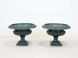 pair of green urns on pedestals on a white surface