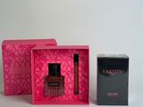an image of a bottle of perfume in a pink box next to a box of perfume