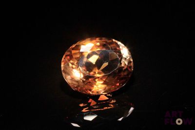 a close up of an orange diamond on a black surface