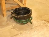 un pot noir posé par terre à côté d'une chaise en bois