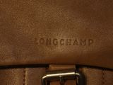the back of a brown leather bag with a metal buckle on it