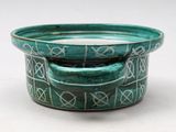a green bowl with writing on it sitting on a table